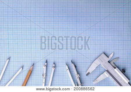 Measuring instruments on top of blue graph paper.