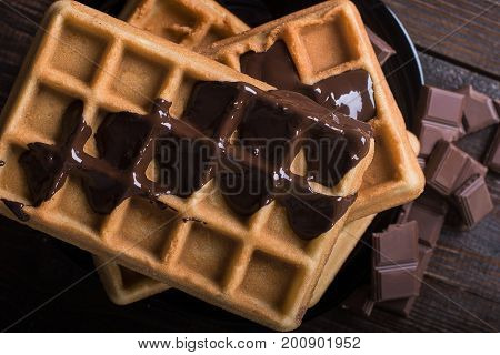 Homemade belgian waffles with melted dark chocolate, closeup. Top view