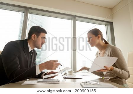 Side view of colleagues arguing at workplace, executives disagree about papers, found error in contract, mistake in paperwork, business partners having claims to documents, disputing over agreement