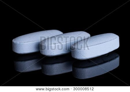 Closeup Of Three Whole Blue Medical Drug Isolated On Black Glass