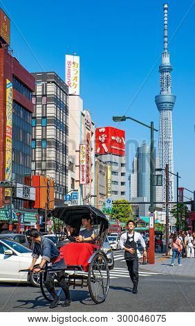 Tokyo, Japan - April 22, 2018: A Rickshaw In The Traffic Of The Asakusa District With The Tokyo Sky 