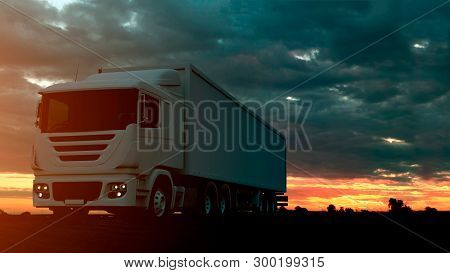Large Freight Truck Driving On A Highway At Sunset Backlit By A Bright Orange Sunburst Under An Omin