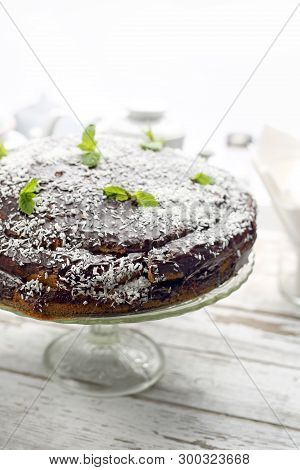 Chocolate Cake With A Chocolate Coating And Coconut Chop Decoration.