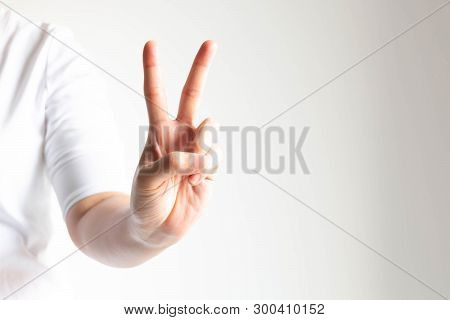 Woman In White T-shirt Stretch Out Her Hand Forward And Raising Forefinger And Middle Finger For Mea