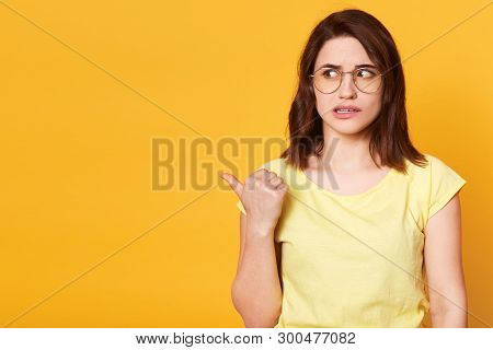 Good Looking Brunette Female Dressed In Casual Yellow T Shirt And Stylish Eyeglasses, Looking Aside,