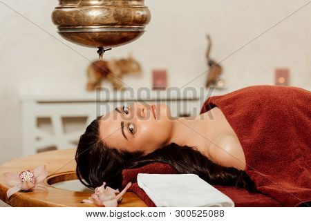 Relaxed Young Woman Lying Under Shirodhara Vessel During Ayurvedic Procedure