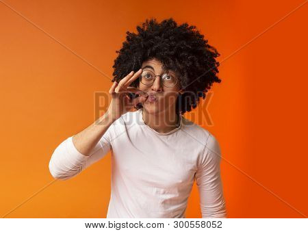 Secret Is Safely Hidden. Black Millennial Guy Locking Mouth Like Zip-lock, Orange Studio Background