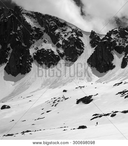 High Mountains With Snow Cornice And Avalanche Tracks, Snowy Plateau And Small Silhouette Of Hiker A