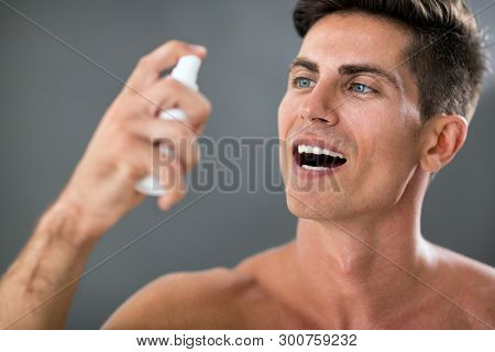 Attractive man applying fresh breath spray