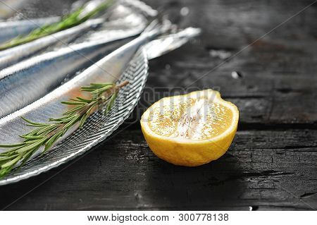 Half A Lemon And Raw Saury On A Glass Dish With Rosemary And Lemon