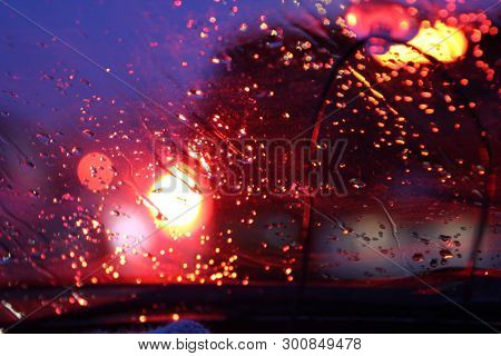 Traffic Is Viewed Through The Car's Windshield Covered In Rain, . Beautiful Background Of Rain And L