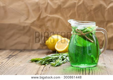 Summer Cold Green Drink Made From Tarragon, With Mint And Slices Lemon In Glass Decanter In Focus An