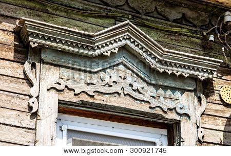 Russian Traditional Wooden Architecture. Facade Of An Old House Decorated With Wooden Carvings, Plat