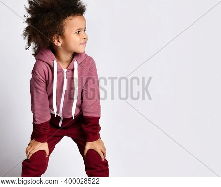 Fashion Advertising In Childhood. Dark Skinned School Age Girl Dressed In A Burgundy Sports Suit Pos
