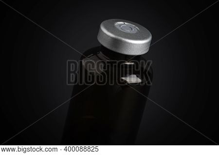 A Macro Shot With Selective Focus Of An Amber Color Vaccine Injection Bottle Set On A Dramatic Black