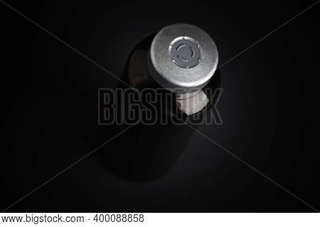 A Macro Shot With Selective Focus Of An Amber Color Vaccine Injection Bottle Set On A Dramatic Black