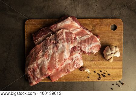 Fresh Pork Ribs Lie On A Wooden Board. Cooking For Frying With Garlic, Top View.