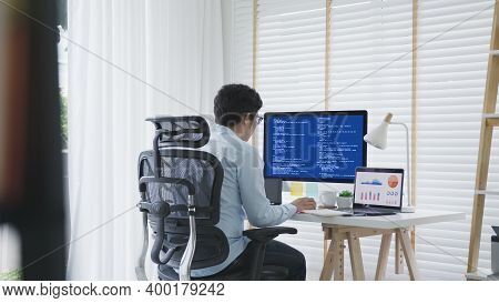 Back Rear View Of Young Asian Man, Freelance Data Scientist Work Remotely At Home Coding Programing 