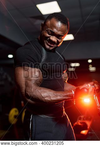 Man Doing The Exercises In Gym. Photo Of Young Man In Black Shirt On Modern Gym Background. Strength