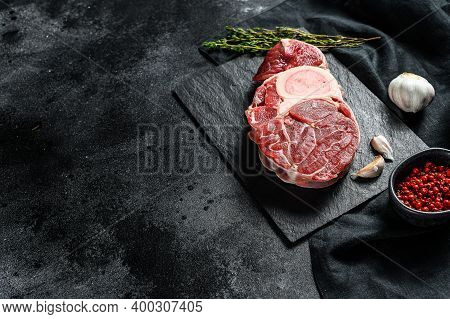 Osso Buco Meat. Raw Cross Cut Veal Shank And Seasonings For Cooking Osso Buco. Black Background. Top