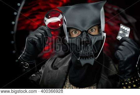 A Man Wearing A Demon Skull Mask In A Leather Cloak With A Magnifying Glass And Pills - Doctor Evil