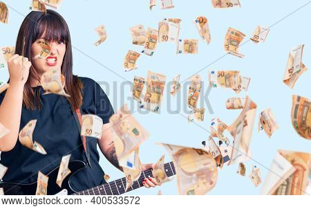 Young plus size woman playing electric guitar annoyed and frustrated shouting with anger, yelling crazy with anger and hand raised