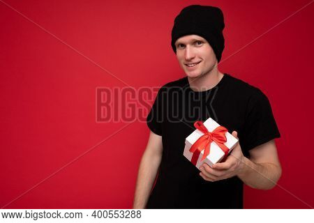 Shot Of Handsome Happy Young Man Isolated Over Red Background Wall Wearing Black Hat And Black T-shi