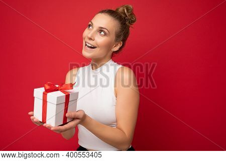 Photo Shot Of Beautiful Positive Thoughtful Young Blonde Woman Isolated Over Red Background Wall Wea