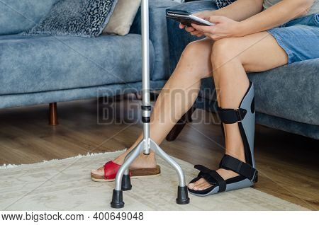 The Woman With A Orthotics On Her Foot Is Sitting On The Sofa At Home