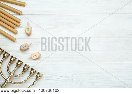 Golden Menorah, Yellow Candles And Hanukkah Dreidels With He, Nun, Gimel Symbols On White Wooden Tab