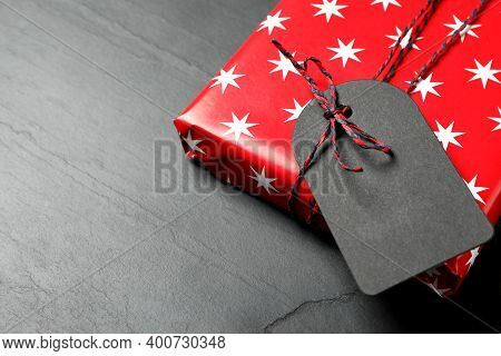 Wrapped Present With Blank Tag On Black Background, Closeup. Space For Text