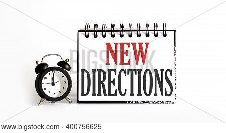 New Directions Notepad Writing On White Background With Alarm Clock