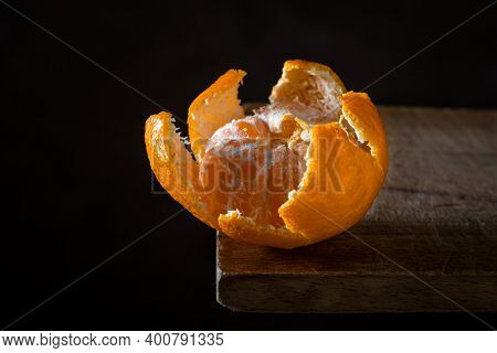 Peeled Tangerine On A Wooden Surface. Citrus Fruit. Peeled Tangerine Lies In Tangerine Peel