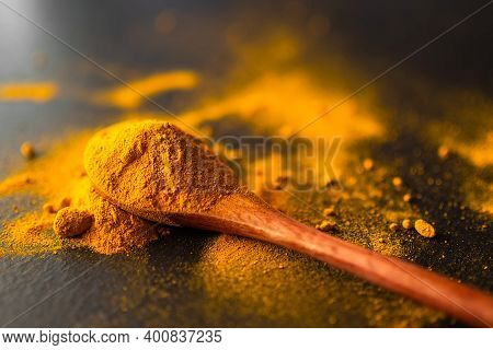Turmeric Powder On Wooden Spoon With Black Background. . Plants Containing Substances Curcuminoids. 