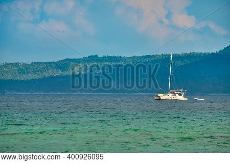 Philippines, Boracay Island, Puka Beach. A White Yacht Is Moored In The Sea With A White Rubber Boat