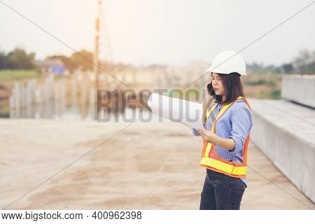 Beautiful Asian Female Engineer In White Safety Hard Hat Doing Job At Construction Site Outside Offi