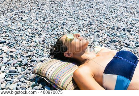Young Caucasian Woman Head Lay On Pillow With Rocky Beach Beackground