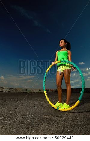 woman rotates hula hoop against blue sky 