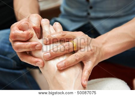 Masseur making a traditional chinese foot massage to adult leg and foot