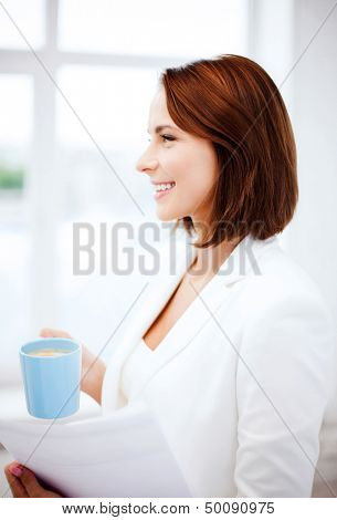 business concept - businesswoman with cup of coffee and papers in office
