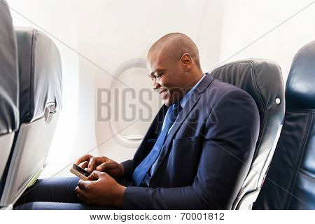 happy african airplane passenger using smart phone on plane