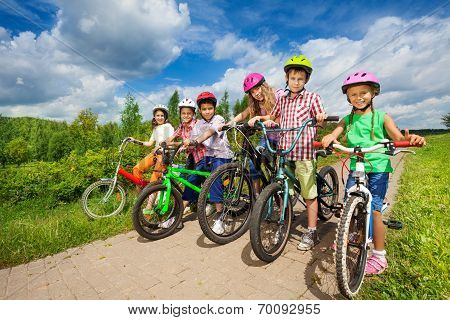 Children in row wearing helmets holding bikes