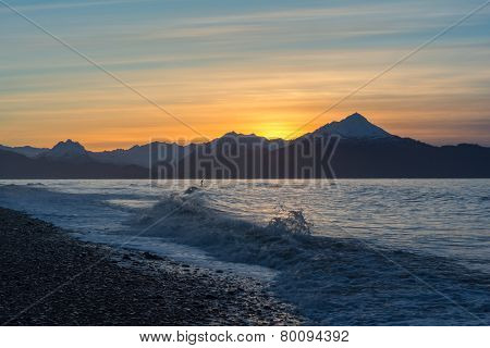 Surfer in waves at sunrise