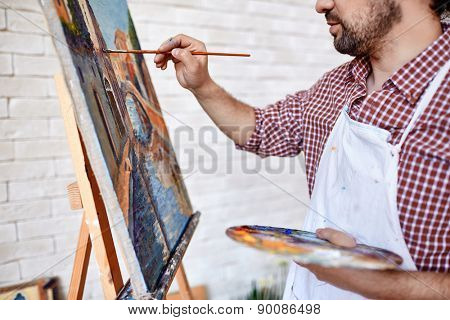 Young artist painting with oilpaints on canvas