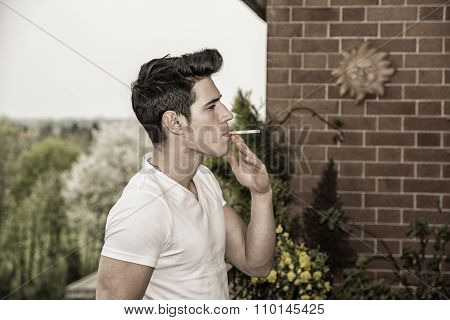 Handsome young man smoking a cigarette outside