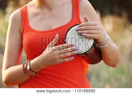 View on a girl playing jembe in the forest close-up