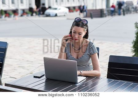 Beautiful female using laptop computer while sitting in coffee shop in the city