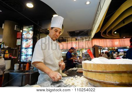 SINGAPORE - NOVEMBER 08, 2015: cook prepare food on the food court of The Shoppes at Marina Bay Sands. The Shoppes at Marina Bay Sands is one of Singapore's largest luxury shopping malls