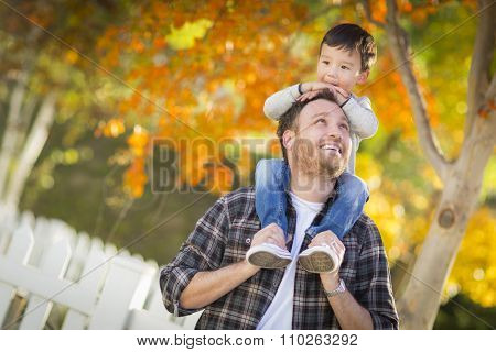 Happy Mixed Race Boy Riding Piggyback on Shoulders of Caucasian Father.