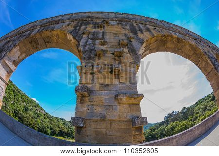 Part of the bridge. One bridge span is photographed lens Fisheye. Three-tiered aqueduct Pont du Gard - the highest in Europe. Provence, spring sunny day